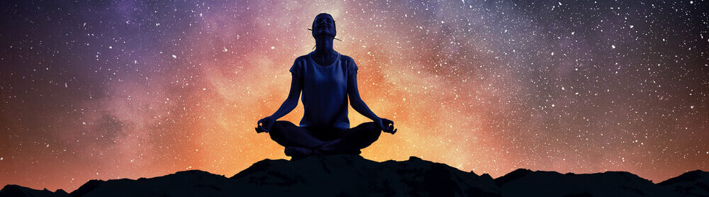 Silhouette of woman against starry sky meditating in lotus pose